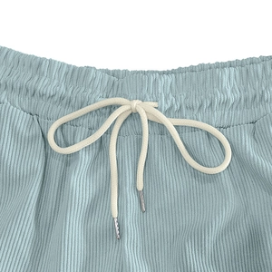 Detail of light blue corduroy shorts with elastic waist and white woven drawstring ties