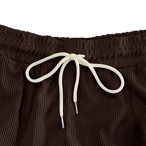 Detail of deep brown corduroy fabric with elastic waistband and white drawstring ties