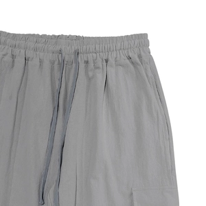 Detail of grey linen pants featuring elastic drawstring waist and side cargo pockets