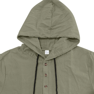 Detail of green linen hoodie shirt showing brown wooden buttons and drawstring fabric texture