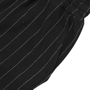 Detail of black striped linen set showing elastic waistband and side pocket texture