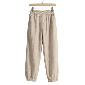 Detail of beige cotton linen joggers featuring elastic drawstring waist and side pockets