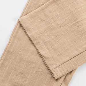 Detailed close-up of light brown linen trousers fabric with white vertical stripes texture