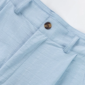 Macro detail of men's linen striped pants showing amber button and waist stitching