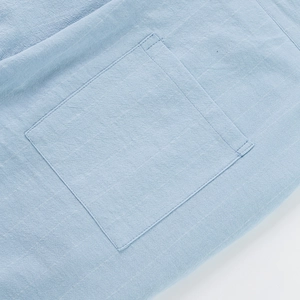 Detail shot of the square pocket and double stitching on light blue linen pants