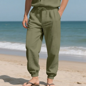 Men's olive linen jogger pants with drawstring waist shown on a sunny beach setting