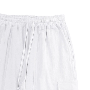 Detail view of white linen pants featuring elastic waistband with drawstring and pockets