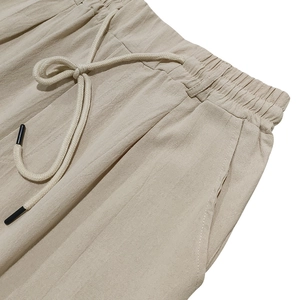Detail of men's linen trousers featuring elastic waistband with drawstring and side pocket