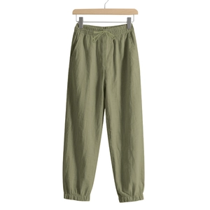 Detail view of olive green linen trousers featuring elastic drawstring waist and cuffed ankles