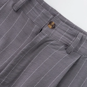 Detail view of dark grey striped linen pants showing amber button and waist stitching