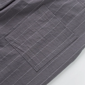 Close-up of linen fabric texture and square patch pocket on dark gray striped trousers