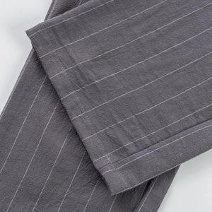 Macro shot of dark grey linen trousers showing fine white stripes and woven texture details