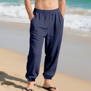 Close-up of men's navy linen beach pants with drawstring waist and elastic cuffs on sand