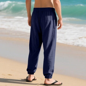 Rear view of men's navy blue linen jogger pants on beach background with elastic cuffs