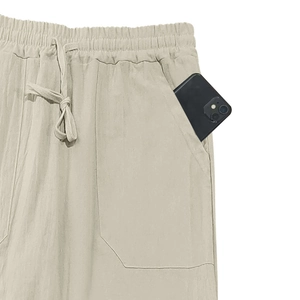 Detail of loose linen pants featuring elastic drawstring waist and large side pocket with phone