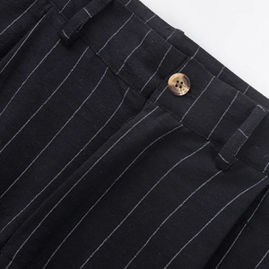 Detail of pinstripe linen trousers showing waist button and textured black fabric