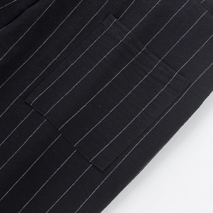 Macro detail of vertical white pinstripes and square patch pocket on black linen trousers