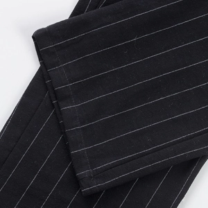 Detailed close-up of hem stitching and white pinstripe texture on black linen pants