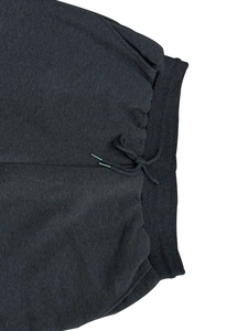Detail of dark grey fleece joggers featuring ribbed elastic waistband and drawstring