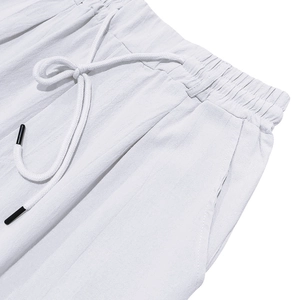 Detailed macro view of white linen pants featuring elastic waistband and drawstring cords
