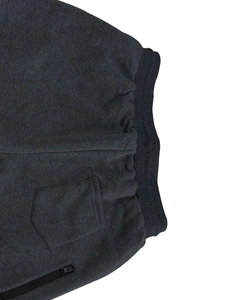 Detail of dark grey jogger pants featuring elastic ribbed waist and secure zipper pockets