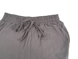 Detailed close-up of dark grey linen trousers featuring elastic waistband and woven drawstring