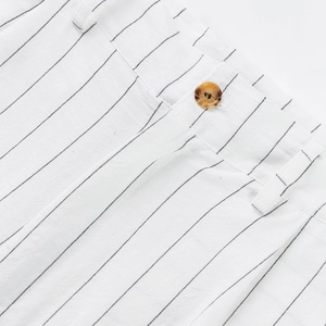 Macro detail of men's linen striped trousers featuring belt loops and amber resin button