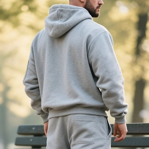 Rear view of men's thick grey fleece hoodie and jogger pants in an outdoor park setting