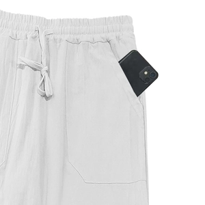 Detail view of white linen pants featuring elastic waistband with functional deep side pockets