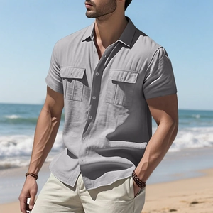 Detail of light grey short-sleeved linen shirt featuring cargo pockets on a beach