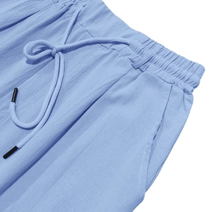 Detail of light blue linen pants showing elastic drawstring waist and side pocket texture