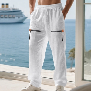 Detail of white linen pants featuring decorative black zipper pockets and drawstring waist