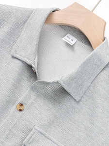Detail of waffle knit fabric texture and pocket on men's casual grey shirt with button