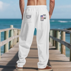 Close-up of white linen trousers with graffiti pockets on a seaside wooden pier