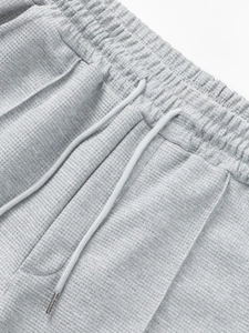 Detail of waffle knit trousers featuring elastic waistband and adjustable drawstring