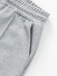 Detail of grey waffle knit shorts featuring elastic waistband and side pocket