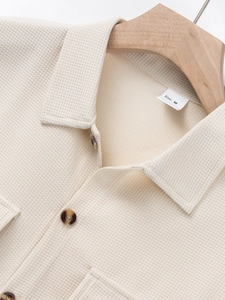 Detailed macro view of waffle knit texture and classic lapel collar on cream shirt