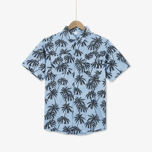 Detail of light blue tropical shirt featuring black coconut palm prints and chest pockets