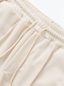 Detail of cream waffle knit fabric shorts with elastic waistband and woven drawstring