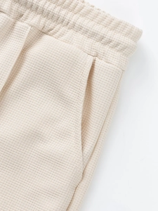 Detailed macro view of waffle knit texture, elastic waistband and pocket on men's cream shorts