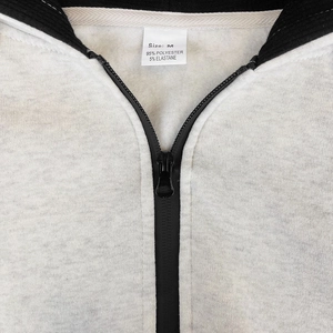 Detail shot of men's gray jacket featuring black waterproof zipper and ribbed collar