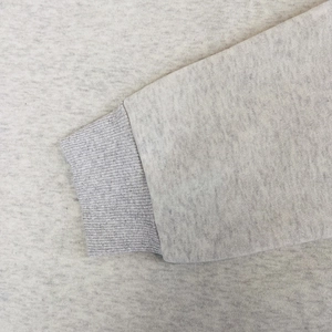 Detailed close-up of a heather grey ribbed cuff on a cotton fleece hooded sweatshirt