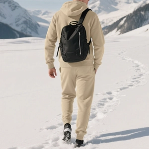 Rear view of man in beige hooded fleece tracksuit walking on snowy mountain terrain