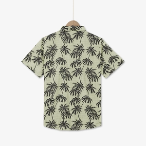 Close-up of olive green Hawaiian shirt featuring black coconut tree prints and light fabric