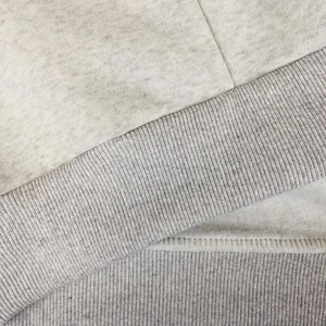 Macro shot of heather grey hoodie featuring ribbed hem and soft fleece lining texture