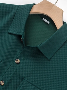 Detail of dark green waffle fabric men's shirt with buttons and chest pocket texture