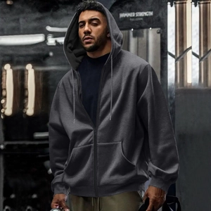 Detail of dark grey zip-up hoodie featuring heavy cotton fabric and ribbed cuffs in a gym