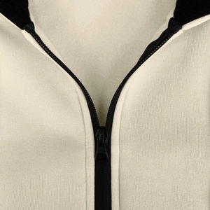 Detailed macro view of the cream fleece hoodie neck and contrast black zipper closure