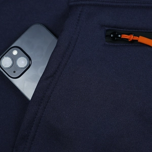 Detail of navy blue joggers showing a deep side pocket with orange zipper and smartphone