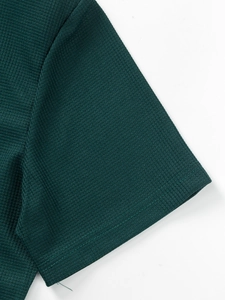 Detailed close-up of dark green waffle fabric texture and stitching on shirt sleeve
